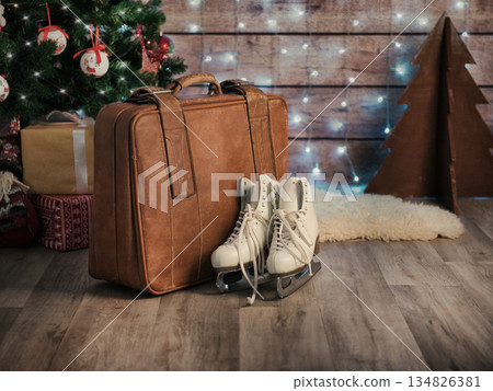 Women's skates next to an old leather suitcase and a Christmas tree. Christmas Decorations 134826381