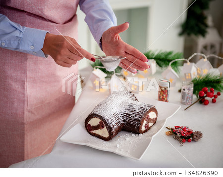 Chocolate cupcake on the New Year's table, Women's hands decorate the cake with powdered sugar. A festive concert Chocolate cupcake on the New Year's table, Women's hands decorate the cake with powdered sugar. A festive concert 134826390