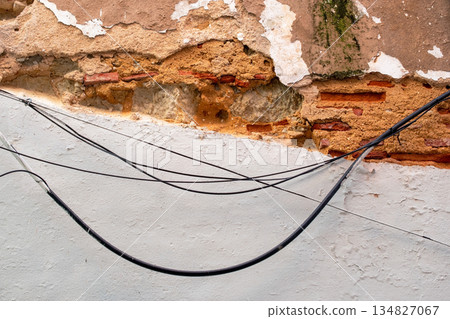 Weathered Urban Wall with Exposed Wires and Crumbling Plaster Weathered Urban Wall with Exposed Wires and Crumbling Plaster 134827067