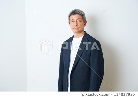 一位身穿夾克和牛仔褲的老者站在那裡 一位身穿夾克和牛仔褲的老者站在那裡 134827950