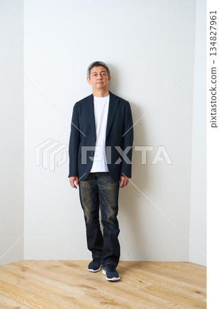 一位身穿夾克和牛仔褲的老者站在那裡 134827961