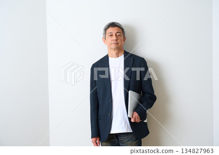 一位身穿夾克和牛仔褲的老者站在那裡 134827963