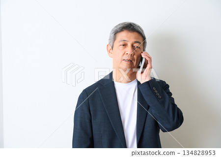 一位老年男子在白色背景上打電話 134828953