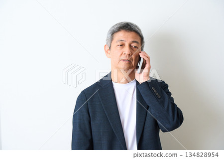 一位老年男子在白色背景上打電話 134828954