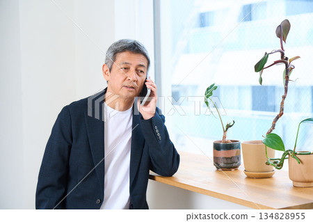 Senior man making a phone call by the window 134828955