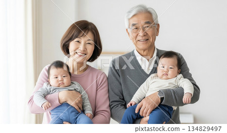Twins being held by smiling grandparents. Family ties and happy moments. Copy space. 134829497