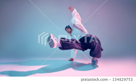 Street dancer performing expressive movement in colorful studio 134829753