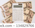 Calculator and scattered Japanese 10,000 yen coins 134829766