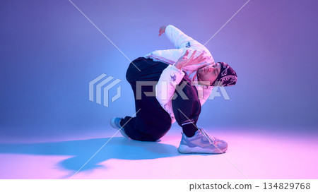 Contemporary dancer performing floor movement in neon colored studio. 134829768