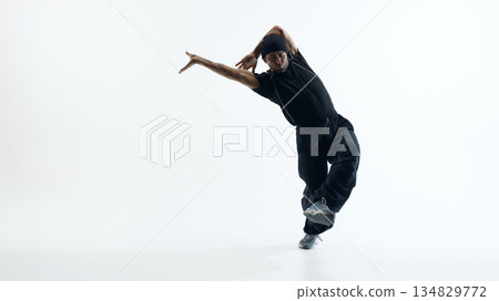 Male dancer performing dynamic jump in studio space. Male dancer performing dynamic jump in studio space. 134829772