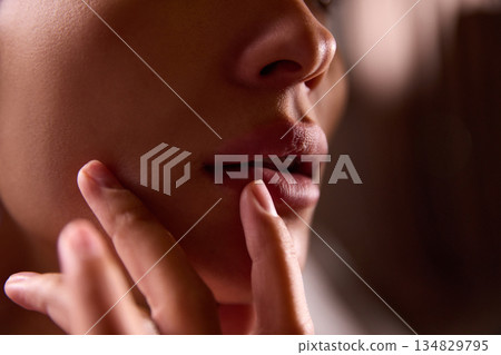 Close up of woman face with fingers touching chin. Close up of woman face with fingers touching chin. 134829795