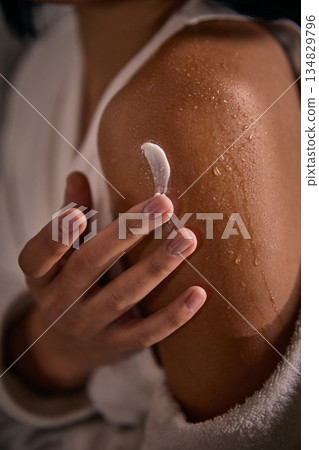 Close up of woman applying cream on wet shoulder skin. Close up of woman applying cream on wet shoulder skin. 134829796
