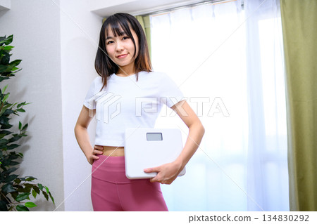 Smiling Japanese woman in yoga wear holding a weight scale Diet leggings 134830292