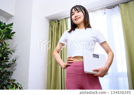 Smiling Japanese woman in yoga wear holding a weight scale Diet leggings 134830293