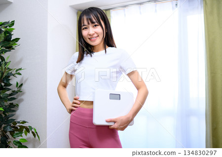 Smiling Japanese woman in yoga wear holding a weight scale Diet leggings 134830297