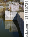 Huge cubic and geometric stone shapes are reflected in the water of the abandoned marble quarry 134830724