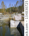 Huge cubic and geometric stone shapes are reflected in the water of the abandoned marble quarry 134830725