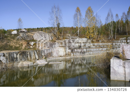 Huge cubic and geometric stone shapes are reflected in the water of the abandoned arble quarry Huge cubic and geometric stone shapes are reflected in the water of the abandoned arble quarry 134830726