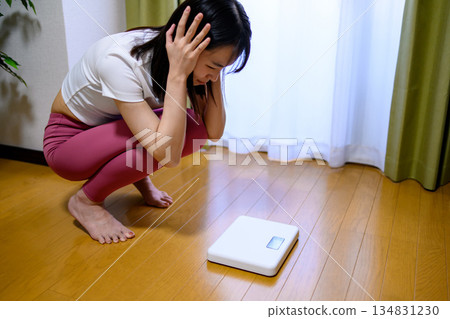 身穿瑜珈服的女子對體重計、飲食和緊身褲感到震驚 身穿瑜珈服的女子對體重計、飲食和緊身褲感到震驚 134831230