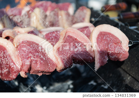 Street food. Grilled roast beef. Grilled picanha. Traditional Brazilian BBQ. Family barbecue. Picanha barbecue roasted over hot coals. Beef meat on BBQ grill. Steak rotisserie at steakhouse grill 134831369