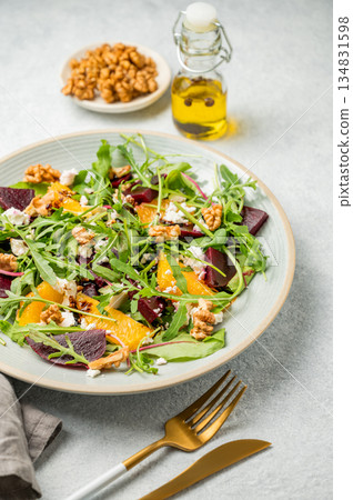 A fresh salad of beets, orange, and arugula with feta, walnuts, and balsamic dressing 134831598