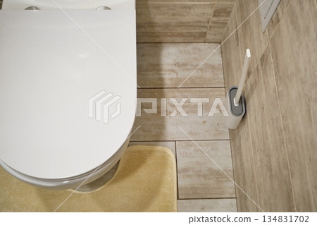 Modern toilet bowl with closed lid and cleaning brush in tiled bathroom Modern toilet bowl with closed lid and cleaning brush in tiled bathroom 134831702