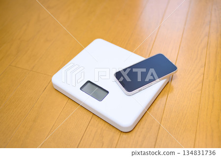 把你的智慧型手機放在地板上的體重計上,看看它如何測量你的體重。 把你的智慧型手機放在地板上的體重計上,看看它如何測量你的體重。 134831736