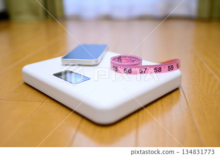 把你的智慧型手機和捲尺放在地板上的秤上。 把你的智慧型手機和捲尺放在地板上的秤上。 134831773