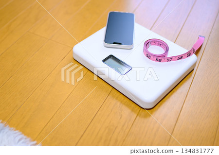 將智慧型手機和捲尺放在地板上的秤上。測量影像已裁切。 將智慧型手機和捲尺放在地板上的秤上。測量影像已裁切。 134831777