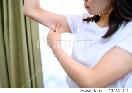 Japanese woman pinching her upper arms to check for sagging. Diet Japanese woman pinching her upper arms to check for sagging. Diet 134831942