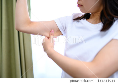 日本女子捏捏自己的上臂,檢查是否鬆弛下垂。 日本女子捏捏自己的上臂,檢查是否鬆弛下垂。 134831944