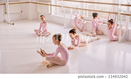 Group of young ballerinas resting and stretching during ballet class. 134832042
