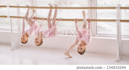 Children practicing upside down ballet exercises at barre indoors. Children practicing upside down ballet exercises at barre indoors. 134832044