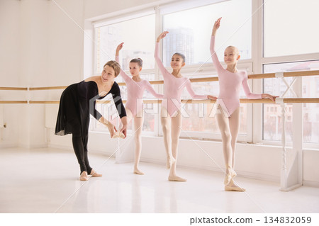 Classical ballet lesson with children practicing coordinated movements at barre. Classical ballet lesson with children practicing coordinated movements at barre. 134832059