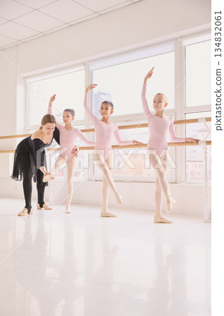 Ballet teacher correcting foot position of young student Ballet teacher correcting foot position of young student 134832061