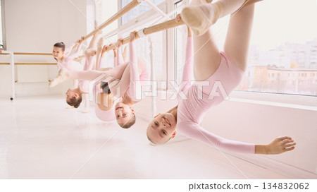 Playful ballet class with children hanging on barre during exercise. Playful ballet class with children hanging on barre during exercise. 134832062