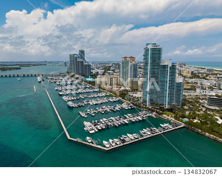 Luxury yacht docked at Miami marina. Aerial view of coastline in Miami. Sailboat cruising along the Miamis shore. Miami skyline above harbor. Famous Miami Beach marine from above. Marina with yachts. 134832067