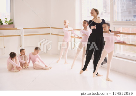 Young ballet students following teacher instructions during barre lesson. 134832089