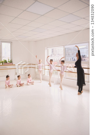 Classical ballet class with teacher demonstrating positions for young students. 134832090