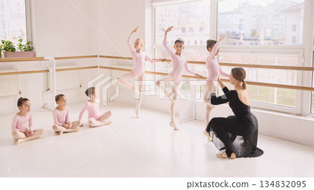 Children ballet class practicing turns and poses with instructor guidance Children ballet class practicing turns and poses with instructor guidance 134832095