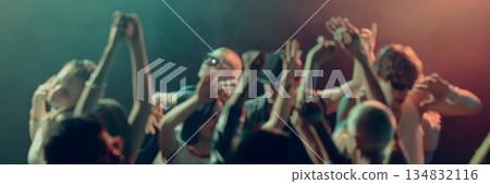 Blurred dancing crowd with hands in motion inside dark club space. Banner 134832116