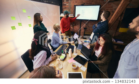 Coworking team reviewing ideas on screen in modern workspace. 134832143