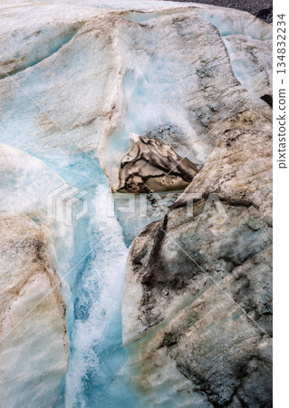 Crevasse in the ice from melting at Athabasca Glacier in Jasper National Park with cloudy sky Crevasse in the ice from melting at Athabasca Glacier in Jasper National Park with cloudy sky 134832234