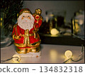 Santa Claus Figurine in Cozy Christmas Setting with String Lights and Decor 134832318