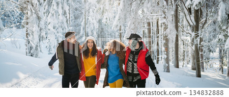 Friends walking through winter forest in snowy landscape. Friends walking through winter forest in snowy landscape. 134832888