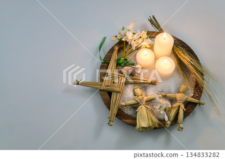 Imbolc altar presenting brigid's cross, candles, and corn dolls 134833282