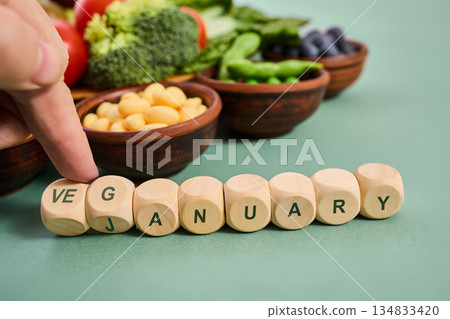 Hand arranging veganuary wooden cubes with healthy vegetables Hand arranging veganuary wooden cubes with healthy vegetables 134833420