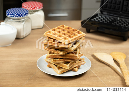 Stack of Homemade Viennese Waffles on a Table with an Electric Waffle Maker Stack of Homemade Viennese Waffles on a Table with an Electric Waffle Maker 134833534
