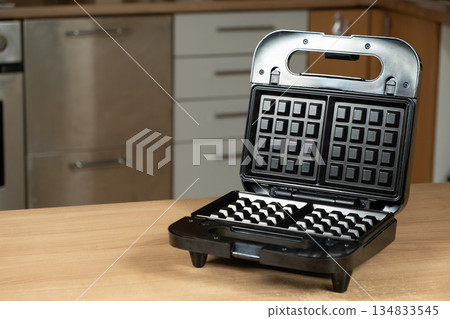 Electric Waffle Maker Appliance Ready for Use on a Wooden Kitchen Countertop. 134833545