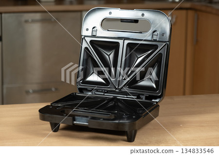 Open Electric Sandwich Toaster Appliance Ready to Use on a Wooden Kitchen Countertop. 134833546